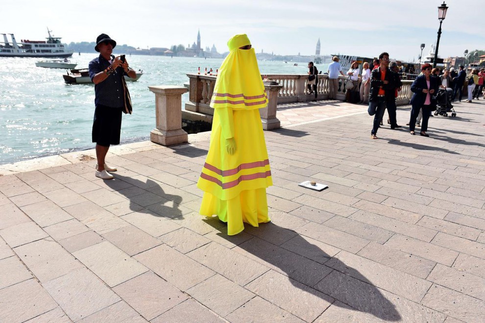 Женщина в желтой бурке показывает перфоманс «High Visibility Burqa» возле места проведения Венецианской биеннале биеннале, выставка, искуссво, скульптура, художник