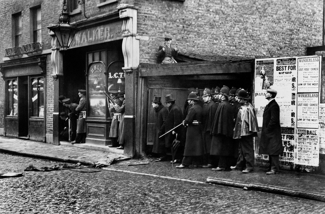 1911. Министр внутренних дел Уинстон Черчилль (слева в цилиндре) во время осады латышской анархистской группировки на Сидней-стрит в Степни, Восточный Лондон. 3 января