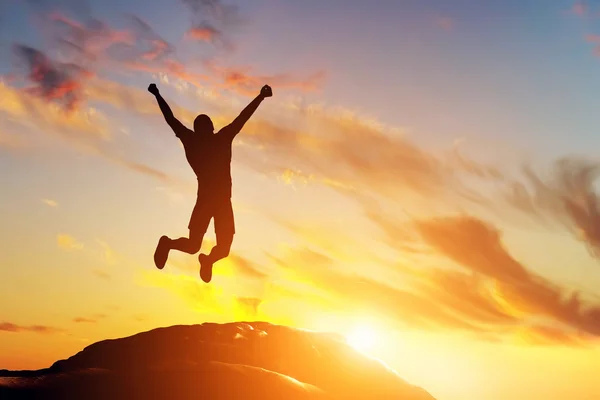 Человек прыгает от радости на пике горы — стоковое фото