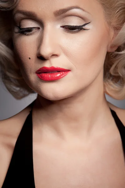Довольно блондинка модель как Мэрилин Монро в черном платье с красными губами на сером фоне — стоковое фото