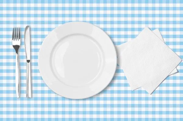 Тарелка, вилка, нож и салфетка над голубой проверенные ткани tableclot — стоковое фото