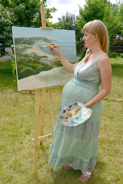 Молодых беременных женщин художник рисует картину масляными красками в t — стоковое фото