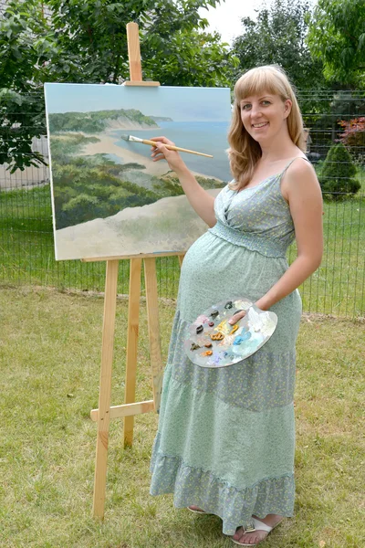 Молодых беременных женщин художник пишет картину с масляной краской — стоковое фото