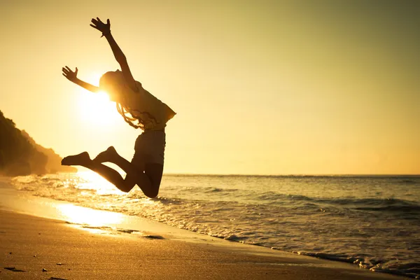Девушка прыгает на пляже в дневное время — стоковое фото