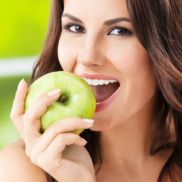 Молодая женщина еда apple, на открытом воздухе — стоковое фото