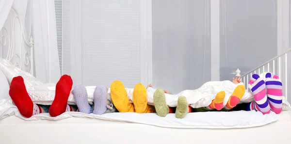 Счастливая семья в красочные носки на белой кровати — стоковое фото