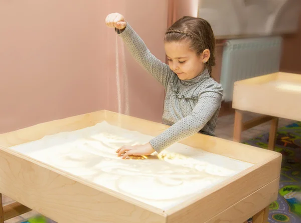 Девушка рисует песком на свет таблицы — стоковое фото