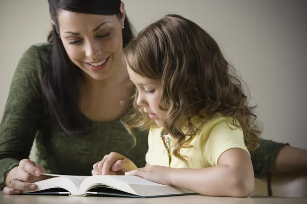 Испаноязычное матери чтения с маленькой дочкой — стоковое фото