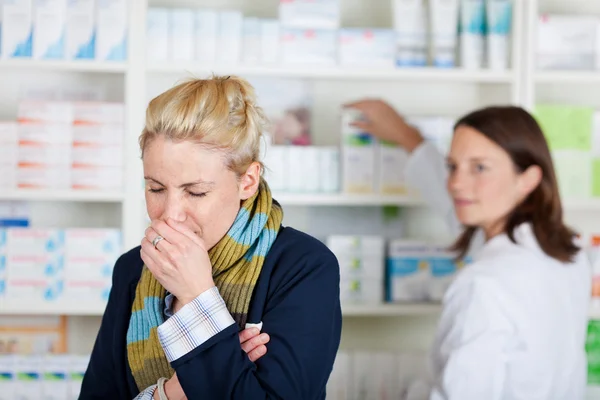 Молодая блондинка женщина, кашель в аптеке — стоковое фото