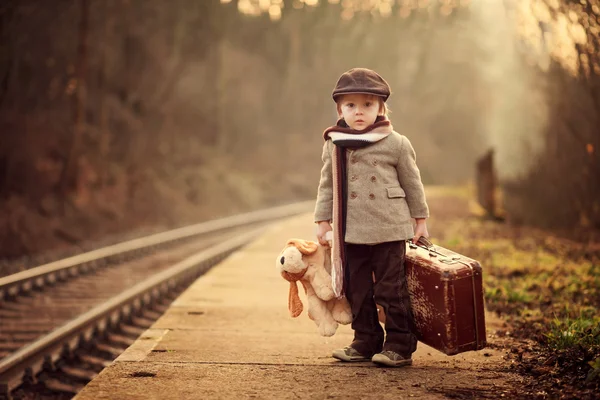 Восхитительный мальчик на железнодорожной станции, ждущей поезда — стоковое фото