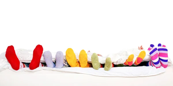 Счастливая семья в красочные носки на белой кровати — стоковое фото