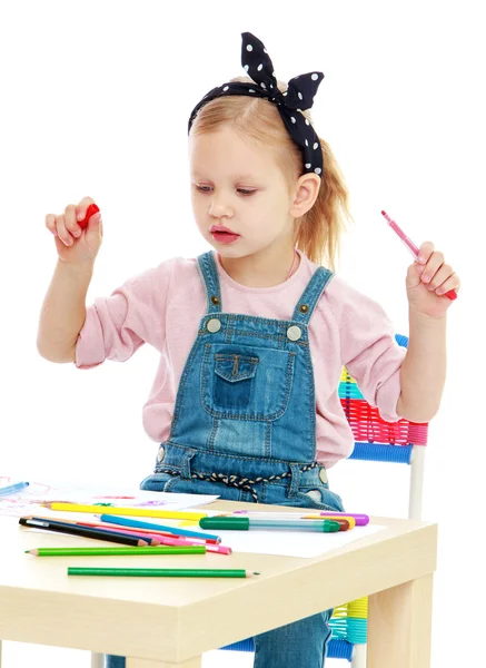Очаровательная маленькая девочка тянет с маркерами, сидя за столом — стоковое фото