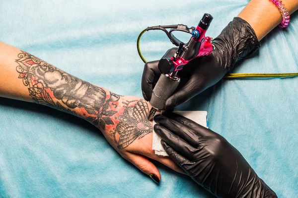 Татуировщик рисует шаблон на руке клиентов — стоковое фото