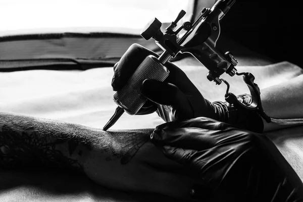 Татуировщик делает татуировки на руке клиентов в bw — стоковое фото