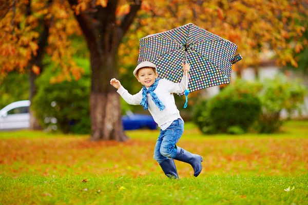Счастливый стильный мальчик с зонтом, работает в парке — стоковое фото