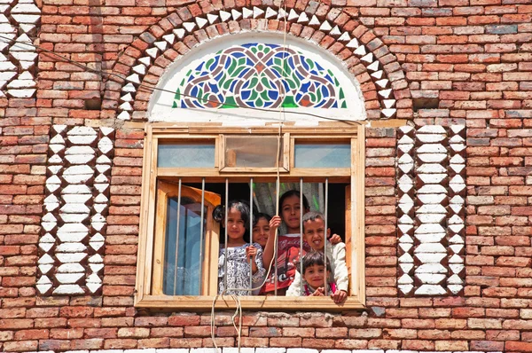 Пять детей, мальчиков и девочек, смотрю в окно в стиле дом старого города Сана, Йемен — стоковое фото