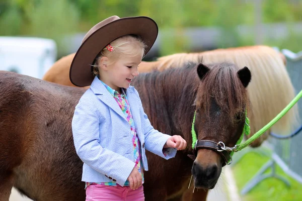 Счастливый маленькая девочка и ее пони — стоковое фото