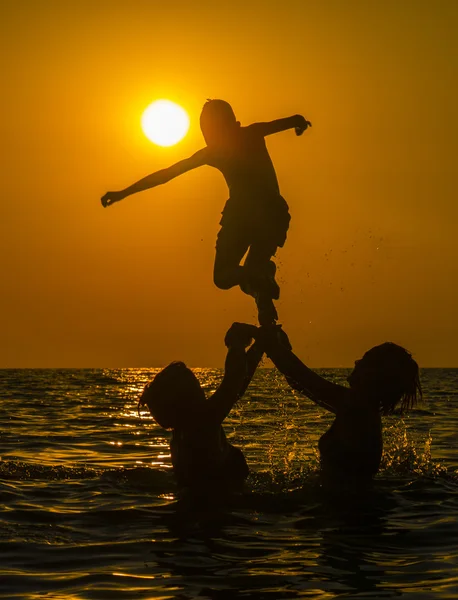 Группа людей, плавание в морской воде на закате — стоковое фото