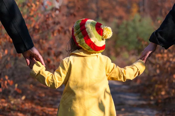 Родители, взявшись за руки маленькой дочери в парке — стоковое фото