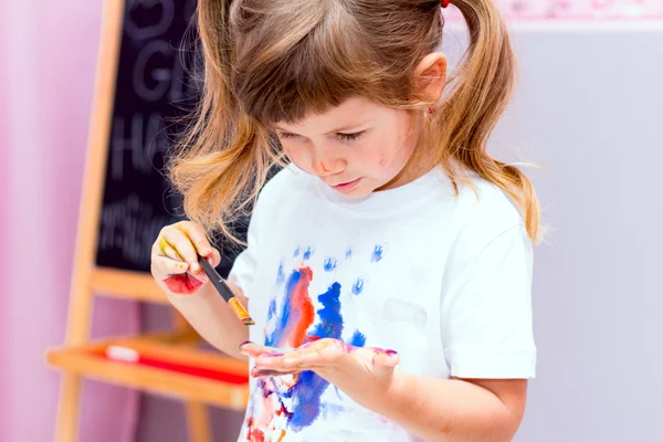 Красивая девочка рисует краски — стоковое фото