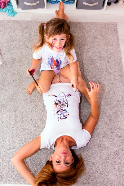 Девушка рисует краски на футболку мать на полу — стоковое фото