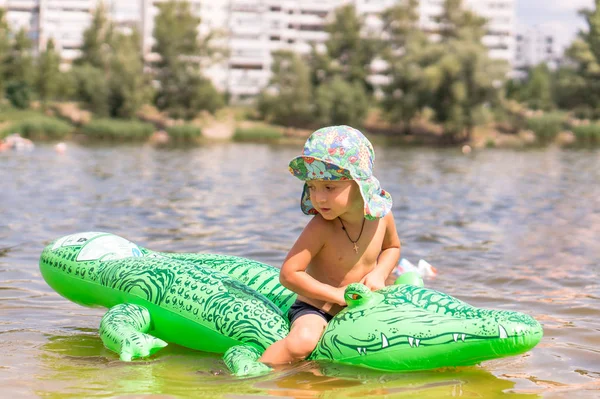 Маленький мальчик играет с игрушкой крокодил в озере — стоковое фото