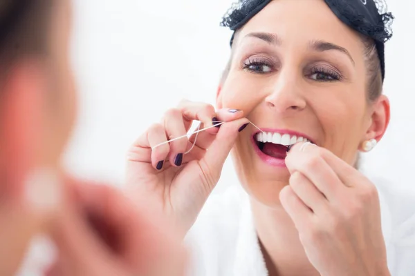Женщина, чистящая зубы с зубной нитью — стоковое фото