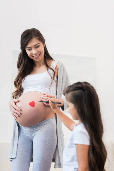 Девушка, опираясь на беременный живот матери — стоковое фото