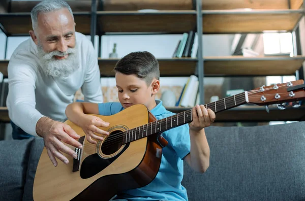 Учитывая старший джентльмен, преподавания внук, играть на гитаре — стоковое фото