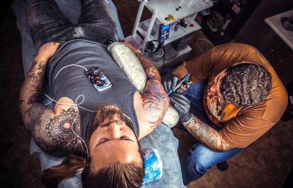 Татуировка специалист, делая татуировки в тату салоне — стоковое фото
