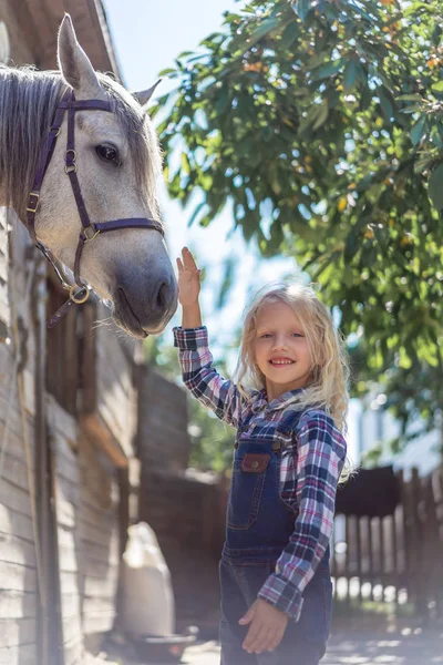 Smiling Kid Touching White Horse Farm Looking Camera — стоковое фото