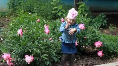 Happy Child girl dances in the garden with peonies. — стоковое видео