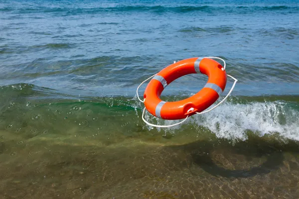 Красный спасательный круг, полет в морской волны — стоковое фото