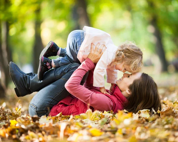 Женщина с ребенком, весело проводящим время в осеннем парке — стоковое фото