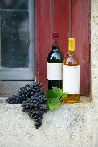 Бутылки вина и грозди винограда на подоконнике — стоковое фото