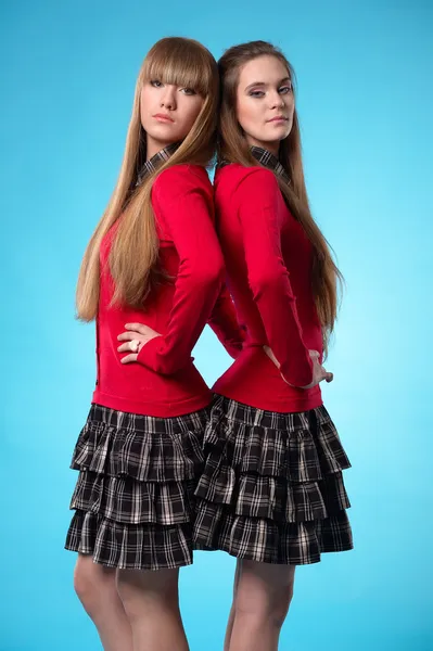 Две школьницы подросток стоять спиной к спине на синем фоне — стоковое фото