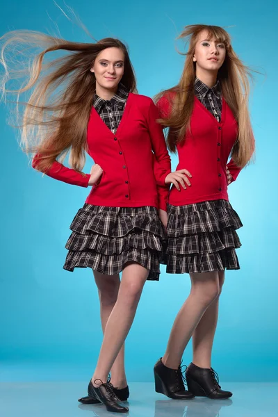 Две школьницы подростков стоять бок о бок на синем фоне — стоковое фото