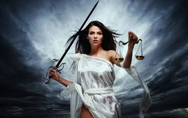 Фемида, богиня справедливости, с весами и мечом против драматических грозовое небо — стоковое фото