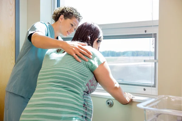 Медсестра утешительное напрягся беременных в окно в больничной палате — стоковое фото