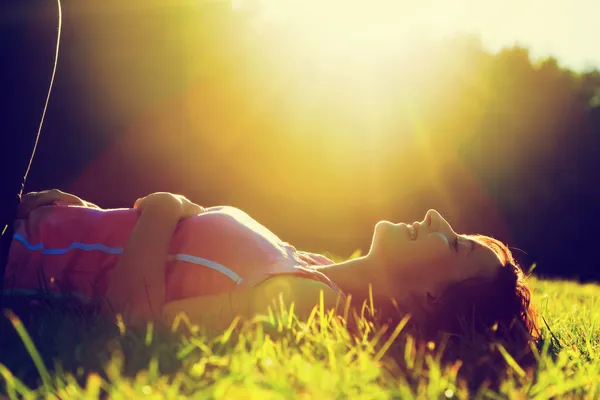 Молодая симпатичная женщина, лежащая на траве на летнем закате — стоковое фото