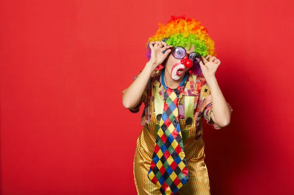 Забавный клоун с бокалами на красном — стоковое фото
