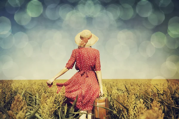 Рыжая девушка с чемоданом на кукурузном поле — стоковое фото