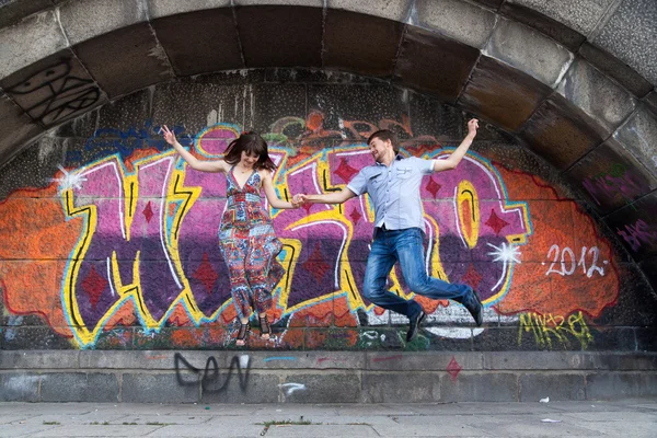 Пара спрыгнуть выступ с фоне граффити — стоковое фото