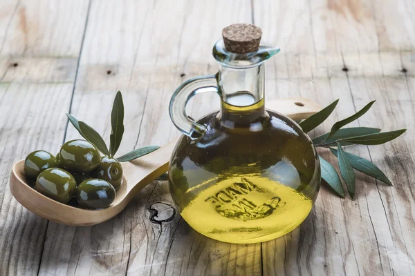 Бутылка оливкового масла и ложку с оливками — стоковое фото