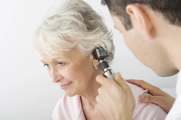 Доктор следственный больного уха с помощью отоскоп — стоковое фото