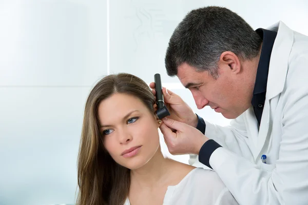 Доктор ЛОР, проверяющий ухо пациентки отоскопом — стоковое фото