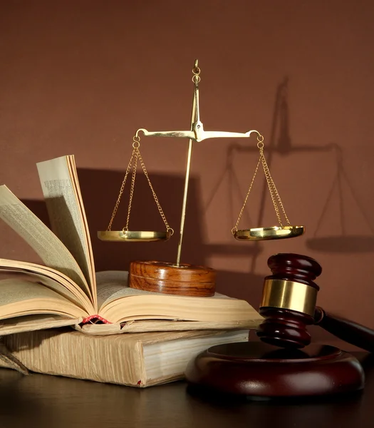 Golden scales of justice, gavel and books on brown background — стоковое фото