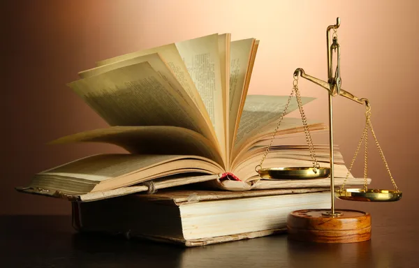 Золотые весы правосудия и книг на коричневый фон — стоковое фото