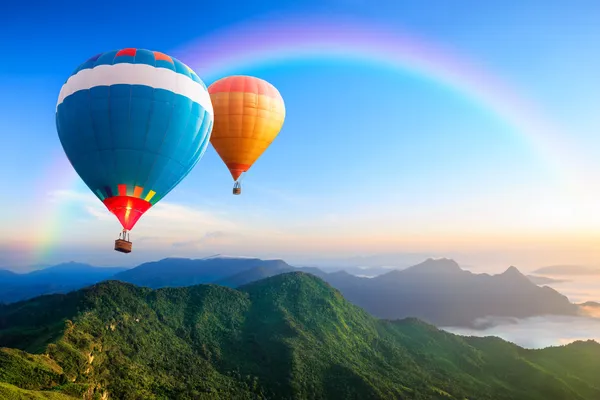 Красочные использующие горячий воздух воздушные шары, пролетающие над горой — стоковое фото
