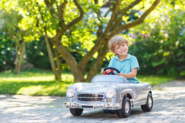 Маленький мальчик вождения большой игрушка старый автомобиль, на открытом воздухе — стоковое фото
